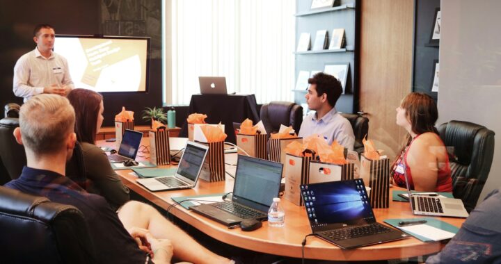 man standing in front of people sitting beside table with laptop computers